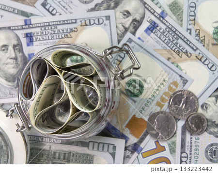Dollars banknotes in a glass jar on bills background. Dollars banknotes in a glass jar on bills background. 133223442