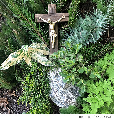 Cross is placed on top of a rock in a garden 133223598