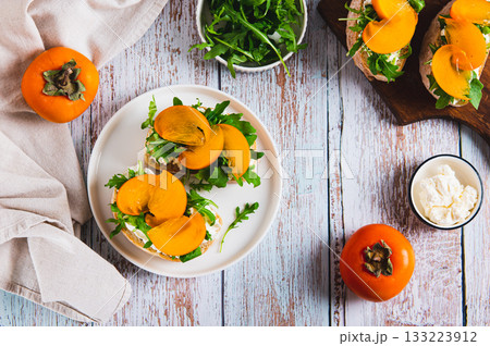 Sweet sandwiches with ricotta, arugula and persimmon on a plate on the table top view Sweet sandwiches with ricotta, arugula and persimmon on a plate on the table top view 133223912