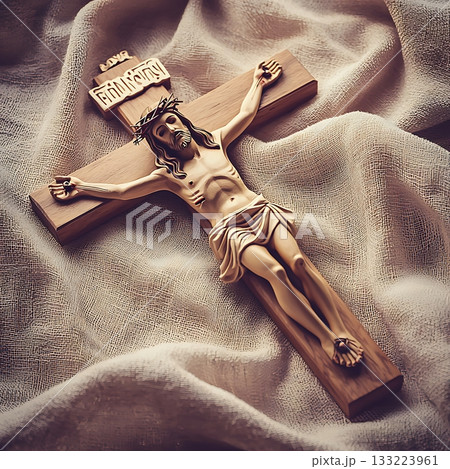Wooden cross with a man's head on it is laying on a white cloth Wooden cross with a man's head on it is laying on a white cloth 133223961
