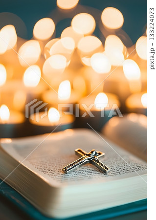 Lit candle sits on top of a book with a cross on it 133224073