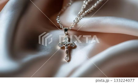 Silver cross necklace is on a white cloth Silver cross necklace is on a white cloth 133224077