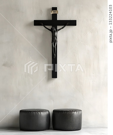 Crucifix is hanging on a wall next to two black leather chairs 133224103