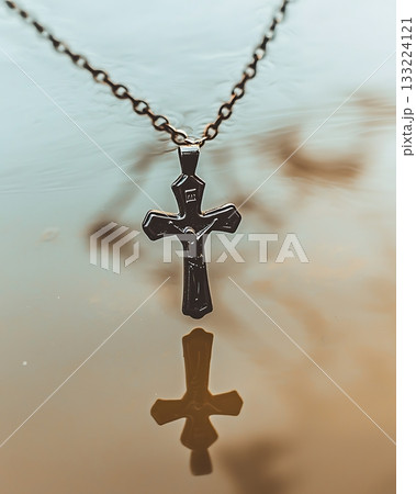 Silver cross necklace is reflected in the water 133224121