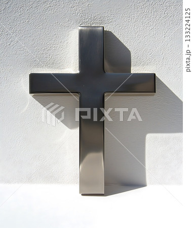 Silver cross is on a white wall 133224125