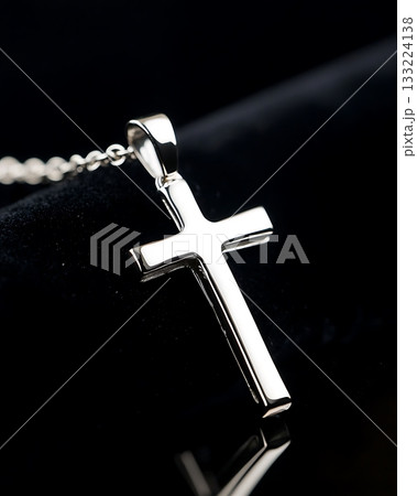 Silver cross pendant is on a black background 133224138