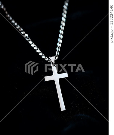 Silver cross pendant is displayed on a black background Silver cross pendant is displayed on a black background 133224140