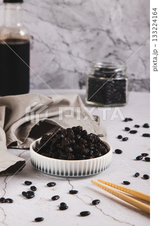 Fermented black douchi beans in a bowl on the table vertical view 133224164