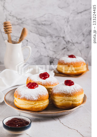Sweet donuts in powdered sugar with jam on a plate on the table vertical view 133224485