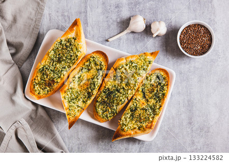 Baked baguette with butter, garlic and dill on a plate on the table top view Baked baguette with butter, garlic and dill on a plate on the table top view 133224582