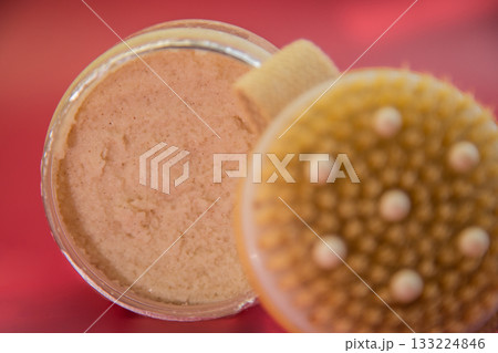 Natural body scrub jar reveals creamy texture inside, with a textured lid, set against a vibrant backdrop, highlighting beauty and wellness themes 133224846