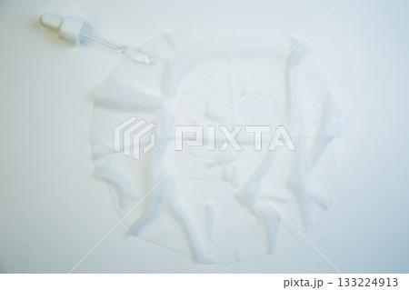 Sheet mask and dropper placed on a pristine white background, highlighting skincare essentials and promoting beauty rituals for rejuvenating and nourishing skin Sheet mask and dropper placed on a pristine white background, highlighting skincare essentials and promoting beauty rituals for rejuvenating and nourishing skin 133224913