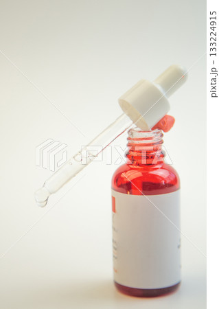 Glass dropper bottle filled with vibrant red liquid, featuring a pipette, perfect for skincare and cosmetic use, highlighting product design and elegance Glass dropper bottle filled with vibrant red liquid, featuring a pipette, perfect for skincare and cosmetic use, highlighting product design and elegance 133224915