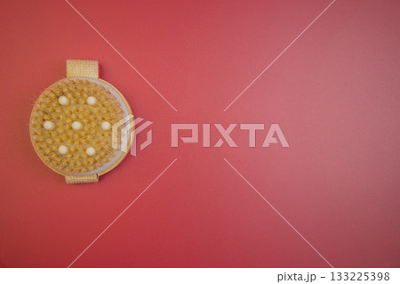 Exfoliating body brush with soft bristles, positioned on bright red surface, highlighting beauty tools for skincare and personal grooming, ideal for self-care routines Exfoliating body brush with soft bristles, positioned on bright red surface, highlighting beauty tools for skincare and personal grooming, ideal for self-care routines 133225398