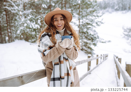 Young woman drinks hot tea while holding a thermos in nature. . Vacation concept Young woman drinks hot tea while holding a thermos in nature. . Vacation concept 133225744