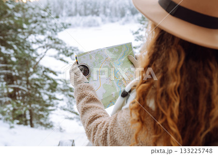 Woman is wearing a winter jacket, hat, scarf and backpack. Enjoying winter travel. Active lifestyle. 133225748