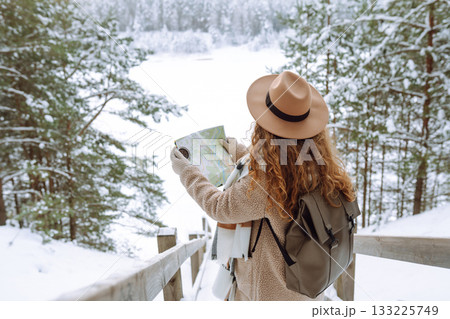 Woman is wearing a winter jacket, hat, scarf and backpack. Enjoying winter travel. Active lifestyle. 133225749