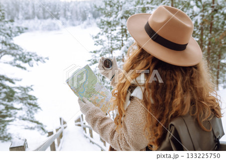Woman is wearing a winter jacket, hat, scarf and backpack. Enjoying winter travel. Active lifestyle. 133225750
