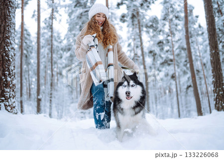 Cute woman spends time with her husky dog in the winter snowy forest. Lifestyle. 133226068