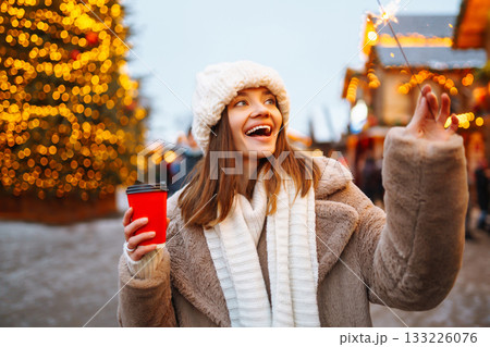 Happy woman with disposable paper coffee cup in winter over outdoor ice skating rink on background. Happy woman with disposable paper coffee cup in winter over outdoor ice skating rink on background. 133226076