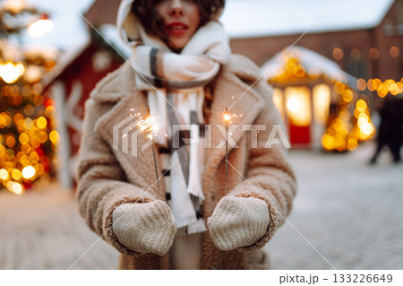 Burning sparklers in woman's hands. Winter holidays. Young smiling woman holding burning sparkler 133226649