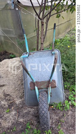 Rustic vegetable garden setting with wheelbarrow for gardening and cultivation inspiration. Vertical poster 133226802