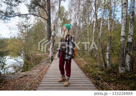 Calm woman meditating and breathing deeply on ecological trail by lakeside in park 133226984