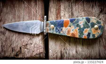 Hand Carved Stone Knife Displayed on Wooden Surface Showcasing Unique Craftsmanship and Colors 133227424