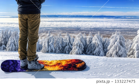 Snowboarder Standing on a Colorful Snowboard Overlooking a Snow-Covered Landscape With Pine Trees Snowboarder Standing on a Colorful Snowboard Overlooking a Snow-Covered Landscape With Pine Trees 133227475