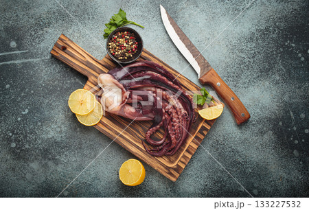 Raw squid octopus wooden cutting board knife gourmet seafood lemon pepper preparing Raw squid octopus wooden cutting board knife gourmet seafood lemon pepper preparing 133227532
