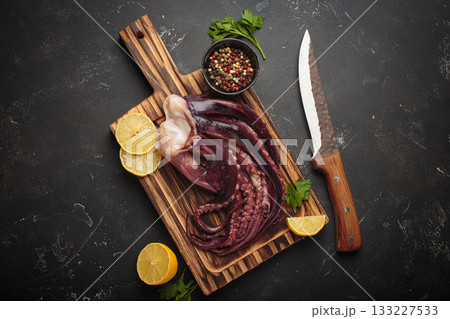Raw squid octopus wooden cutting board knife gourmet seafood lemon pepper preparing Raw squid octopus wooden cutting board knife gourmet seafood lemon pepper preparing 133227533