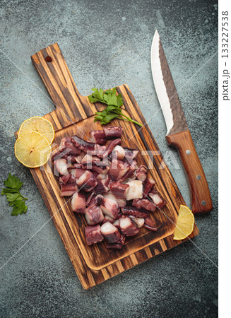 Raw octopus squid cut pieces lemon parsley cutting board cooking seafood knife Raw octopus squid cut pieces lemon parsley cutting board cooking seafood knife 133227538