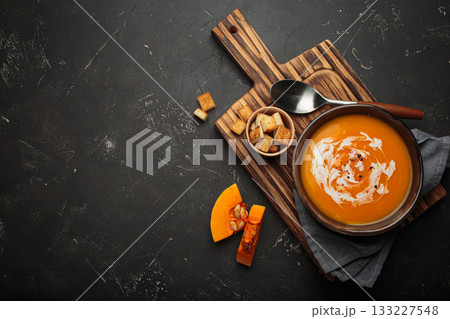 Pumpkin soup croutons cream fresh pumpkin slices wooden board dark background autumn winter copy space Pumpkin soup croutons cream fresh pumpkin slices wooden board dark background autumn winter copy space 133227548