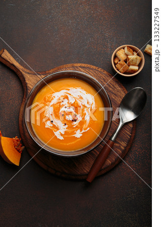 Pumpkin soup croutons cream fresh pumpkin slices wooden board dark background autumn winter 133227549