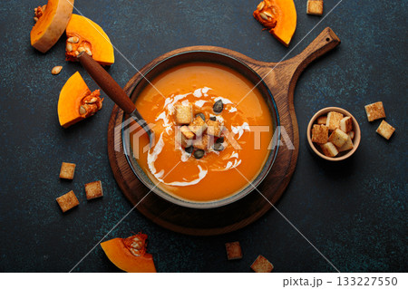 Pumpkin soup croutons cream fresh pumpkin slices wooden board dark background autumn winter Pumpkin soup croutons cream fresh pumpkin slices wooden board dark background autumn winter 133227550