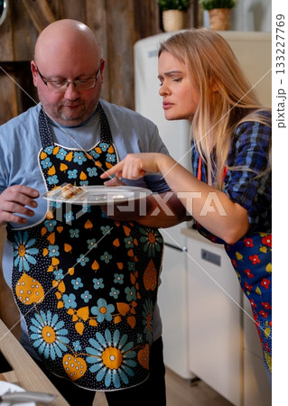 White couple grating cheese for pasta, man using grater while woman holds bowl, cherry tomatoes on wooden board, utensils and relaxed weekend cooking vibe, warm kitchen White couple grating cheese for pasta, man using grater while woman holds bowl, cherry tomatoes on wooden board, utensils and relaxed weekend cooking vibe, warm kitchen 133227769