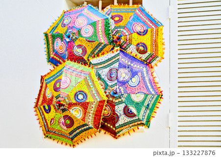 Decoration with colorful embroidered parasols on a white wall. Altea, Alicante Decoration with colorful embroidered parasols on a white wall. Altea, Alicante 133227876