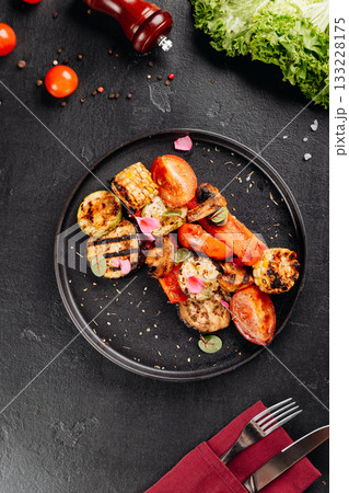 Colorful grilled vegetables with char marks on black plate, close-up, healthy vegetarian dish Colorful grilled vegetables with char marks on black plate, close-up, healthy vegetarian dish 133228175