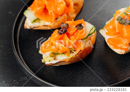 Gourmet salmon canapes on baguette with cream cheese and cucumber on black plate Gourmet salmon canapes on baguette with cream cheese and cucumber on black plate 133228181