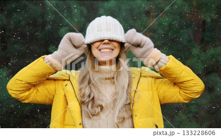 Winter portrait of happy cheerful woman having fun in hat against Christmas tree in forest 133228606