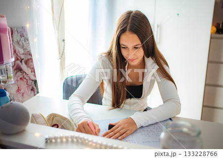 Teenager girl studying homework at desk in bedroom Teenager girl studying homework at desk in bedroom 133228766