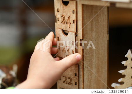 A child opens wooden advent calendar with presents A child opens wooden advent calendar with presents 133229014