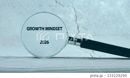A magnifying glass focuses on the words growth mindset and 2026, symbolizing the importance of embracing challenges and fostering a positive attitude toward learning and growth 133229280