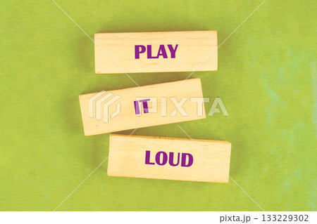Three wooden blocks stacked together display the words Play It Loud, inviting participants to express themselves freely in a vibrant workshop atmosphere filled with creativity and energy Three wooden blocks stacked together display the words Play It Loud, inviting participants to express themselves freely in a vibrant workshop atmosphere filled with creativity and energy 133229302