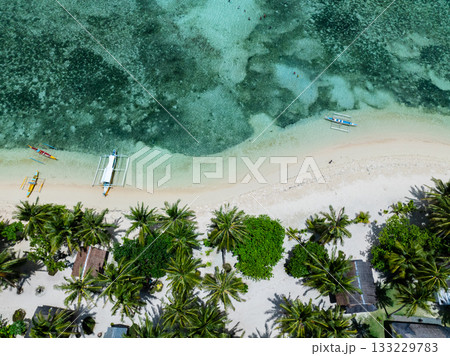 Palm trees on sandy beach with traditional boats along turquoise clear water near coral reef. Siargao, Philippines. Casa Desideria. 133229783