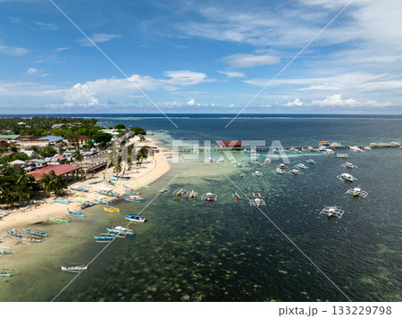 Fishing boats anchored near pier with coastal settlement and sandy shoreline. General Luna, Siargao, Philippines. Fishing boats anchored near pier with coastal settlement and sandy shoreline. General Luna, Siargao, Philippines. 133229798
