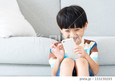 リビングでスマホで遊ぶ小学生男子 133230203