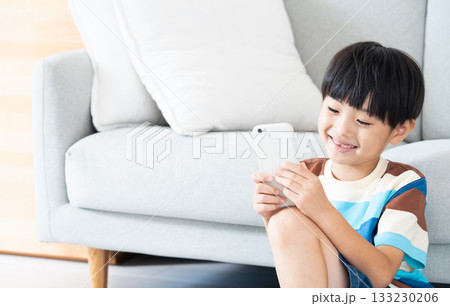 リビングでスマホで遊ぶ小学生男子 133230206