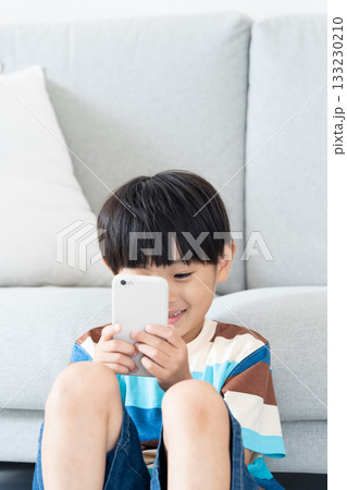 リビングでスマホで遊ぶ小学生男子 133230210
