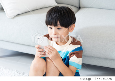 リビングでスマホで遊ぶ小学生男子 133230220